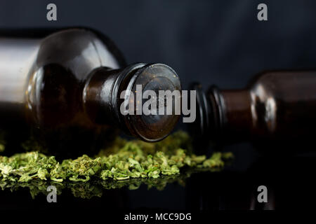 Cannabisknospen und Blumen mit alten Apothekenflaschen auf schwarzem Hintergrund. Stockfoto