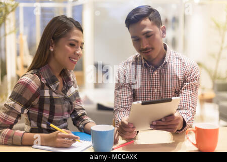 Junger Mann und Frau mit einem Tablet während der Zusammenarbeit an einem Projekt Stockfoto