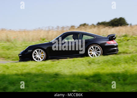 Niedrigen winkel Profil (Seitenansicht) eines schwarzen Porsche 911 997 Turbo schnelle Fahrt auf der öffentlichen Straße. Stockfoto