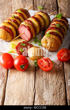 BBQ vom Grill heiße Kartoffel Spieße mit Wurst Salami und grüne Zwiebeln close-up auf den Tisch. Vertikale Stockfoto