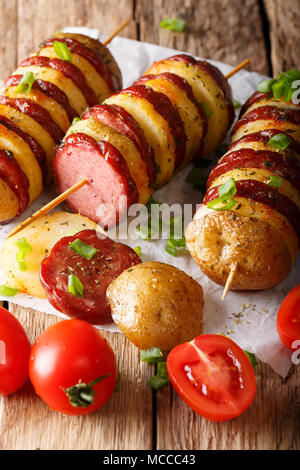 Einfachen snack der Kartoffel Spieße mit Wurst Salami und Frühlingszwiebeln close-up auf dem Tisch. Vertikale Stockfoto