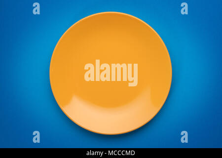 Leere gelbe Platte auf blauem Hintergrund. Ansicht von oben Stockfoto