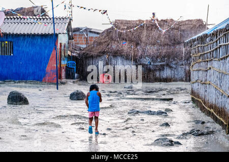 Arme junge Mädchen klatschnass zu Fuß durch Regen in ländlichen Dorf Stockfoto