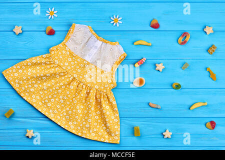 Baumwolle Baby-Girl Dress, Gummi Süßigkeiten. Kleinkind Mädchen Spitze geblümten Kleid auf Blau Holz- Hintergrund, Ansicht von oben. Stockfoto