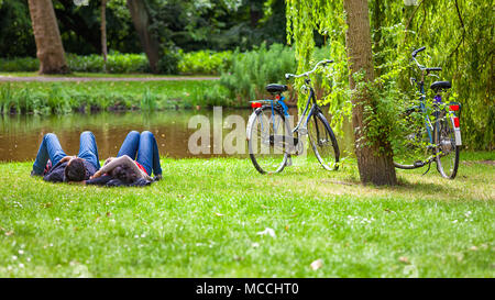 Entspannt Paar auf Gras im öffentlichen Park nach einem Fahrrad reiten, Vondelpark, Amsterdam, Holland Stockfoto