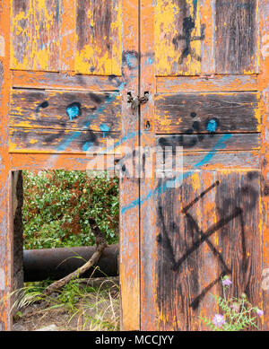 Abblättern/abblätternde Farbe auf alten, verwitterten Holztür mit Hakenkreuz auf Tür lackiert. Stockfoto