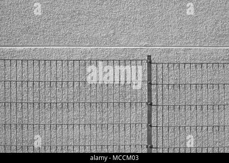 Die Details eines homogenen Lattenzaun vor einem hellen Fassade verputzt. Stockfoto