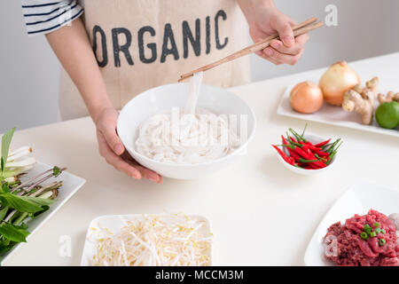 Köchin traditionelle vietnamesische Suppe pho bo mit Kräutern, Fleisch, Reis Nudeln Stockfoto