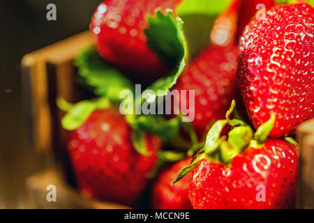 Frische Erdbeeren mit Blättern im Holzkasten schließen Stockfoto