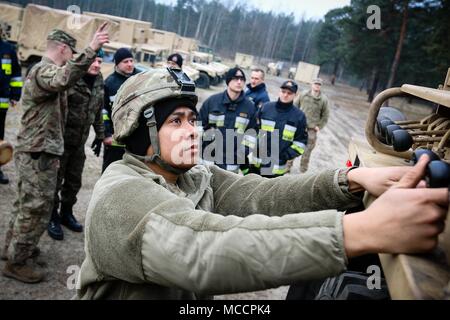 Spc. Kyle Tumanneng, Maui, Hawaii native und ein radfahrzeug Mechaniker mit der 82Nd Brigade Engineer Battalion, 2nd Armored Brigade Combat Team, 1.Infanterie Division, hilft den Mitgliedern der Polnischen 5430rd Militärische Feuerwehr, wie ein M984A4 Wiederherstellungs-Lkw in Zagan, Polen am 8. Februar 2018 zu unterrichten. Tumanneng und seine Kameraden sind ein Teil einer multinationalen Übung entwickelt, um die Interoperabilität zu lösen, während Atlantik erhöhen. (U.S. Armee Foto von SPC. Hubert D. Delany III/22 Mobile Public Affairs Abteilung) Stockfoto