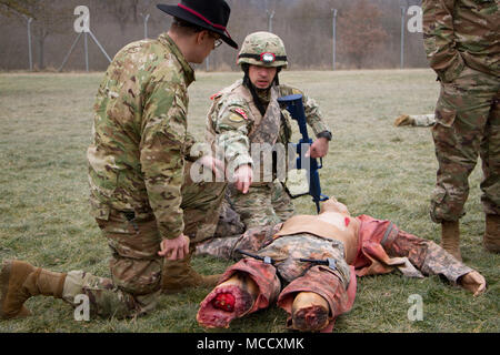 Ein georgischer Soldat von 11 Leichte Infanterie Bataillon, 1 Infanterie Brigade der Georgischen Landstreitkräfte, erklärt, wie er ist ein simulierter Unfall an SPC zu behandeln. Wesley Hobson, eine Bekämpfung der Medic in die 4. Staffel, 2d-Cavalry Regiment zugeordnet, während ein Combat Life Saver Kurs Feb 9, 2018 an der Medizinischen Simulation Training Center in Grafenwöhr Training Area, Deutschland. Die Soldaten sind Training mit US Marine Corpsmen für einen bevorstehenden Einsatz in Afghanistan. Die soldaten Instruktion der Kurs vom 2.Kavallerie Regiments und 7th Army Training Befehl. (Foto: Staff Sgt. Jennifer Bunn) Stockfoto