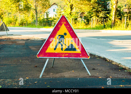 Werke vor Warnschild auf einer Straße. Stockfoto