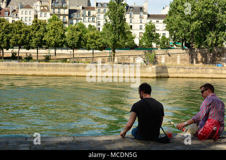 Ein Mann gießt aus einem Getränk für einen Freund, wie sie auf dem Ufer der Seine in Paris, Frankreich. Stockfoto