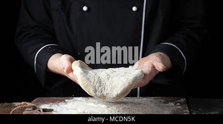 Köchin holding Hefeteig in ihren Händen auf schwarzem Hintergrund. Stockfoto