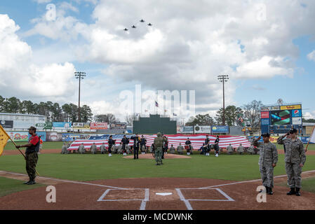 Fast 50 Flieger an James C. Binnicker Flieger-führung Schule bei Seymour Johnson Air Force Base, Nord-Carolina, halten Sie die Fahne 24.02.2018, während vier F-15 E Strike Eagles über Grainger Stadion in Kinston, North Carolina, während der Nationalhymne fliegen vor dem Spiel zwei der Freiheit Classic Baseball Turnier. Die Freiheit Classic ist das jährliche Turnier zwischen der Luftwaffe und der Marine Akademie Baseball Teams, die in Kinston für die letzten acht Jahre gehalten worden ist. (U.S. Air Force Foto von Tech. Sgt. David W. Carbajal) Stockfoto