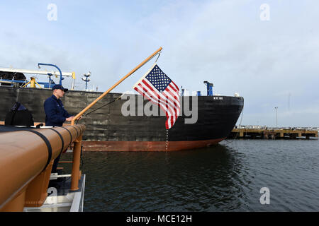 Coast Guard Seaman Jesse Adams, ein Mitglied der Besatzung an Bord Cutter fliegende Fische, Hebezeuge der Flagge während der Morgen Farben bei gemeinsamen Expeditionary Base wenig Creek-Fort Geschichte in Virginia Beach, Virginia, Feb 15, 2018. Die 87-Fuß-Patrouillenboot der 12-köpfigen Crew führt vor allem der Suche und Rettung und der marinen Fischerei Durchsetzung Missionen. (U.S. Coast Guard Fotos von Petty Officer Corinne Zilnicki/Freigegeben) Stockfoto