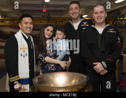 NORFOLK, Virginia (Feb. 27, 2018) - - (von links) Lt.Cmdr. David Kim, der Luftfahrt Bootsmann Mate (Ausstattung) 1. Klasse Andrew Holcomb und seine Familie, und der Luftfahrt Bootsmann Mate (Ausrüstung) in der 2. Klasse Michael Ufer posieren für ein Gruppenfoto nach der Taufe. Der Brauch der tauft Säuglinge an Bord von Schiffen der britischen Royal Navy, in der die Kinder unter oder im Inneren des Schiffes Bell getauft ist. (U.S. Marine Foto von Mass Communication Specialist 3. Klasse Katze Campbell) Stockfoto