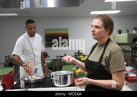 Oberstleutnant Christine Edwards (rechts), eine Armee Ernährungsberater, lehrt Paare die Bedeutung der Planung einer Mahlzeit und zusammen kochen, während Sgt. 1. Klasse Raphael Bonair, eine kulinarische Spezialist mit US-Armee Nord (fünfte Armee) und den eingetragenen Berater von Generalleutnant Jeffery S. Buchanan, der senior Commander für ARNORTH, zeigt, pan-verwelkende Hähnchen Schenkel in der Vogel Ausfallsicherheit Center am Joint Base San Antonio - Fort Sam Houston, Texas Feb.23 während einer Verbindung Bereicherung Klasse. (Foto: Staff Sgt. Tomora Nance U.S. Army North Public Affairs) Stockfoto