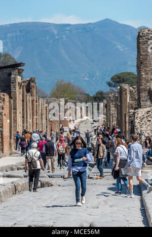 Frau / Frau Touristen zu Fuß zur Mitte der Strasse in Pompeji auf Karte suchen; Touristen, Berg- und Ruinen hinter ihr. Stockfoto