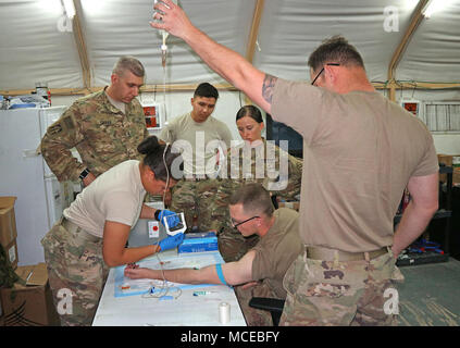 Ärzte mit 38th der Indiana National Guard Sustainment Brigade an Medic Tabelle III Training im Camp Arifjan, Kuwait, am 11. April. Spc. Brianna Lancaster fügt eine intravenöse Leitung in den Arm des SPC. Dalton Vernon als Sgt. 1. Klasse Matthew Caras, medizinische NCOIC, beauftragt, SPC. Samuel Thompson und Sgt. Rachel Wallace von der 824th Transportation Company beobachten, während Staff Sgt. Ryan Kilgore, ein Freiwilliger "Patient", hält die Tasche von Flüssigkeit. (Foto durch Master Sgt. Brad Staggs, 38th Sus Bde Public Affairs) Stockfoto