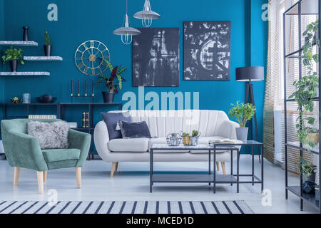 Grün Beige Sofa und Sessel gegen blaue Wand mit schwarzen Gemälde im Wohnzimmer Innenraum Stockfoto