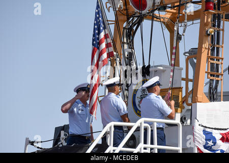 Die Crew der Coast Guard Cutter Edisto senkt die nationalen Ensign und Inbetriebnahme Wimpel während des Edisto Stilllegung Zeremonie am Naval Base Point Loma, San Diego, 13. April 2018. Edisto war nach 31 Jahren stillgelegt. (U.S. Coast Guard Foto von Petty Officer 2. Klasse Joel Guzman / freigegeben) Stockfoto