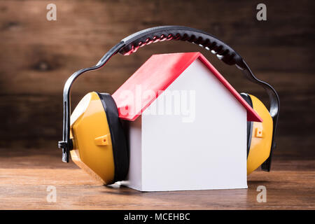 Close-up Arbeiten gelbe Schutzkappe Kopfhörer auf dem Haus Modell über die hölzerne Tabelle Stockfoto