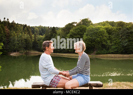 Senior Paar sitzen auf einer Bank am See. Stockfoto