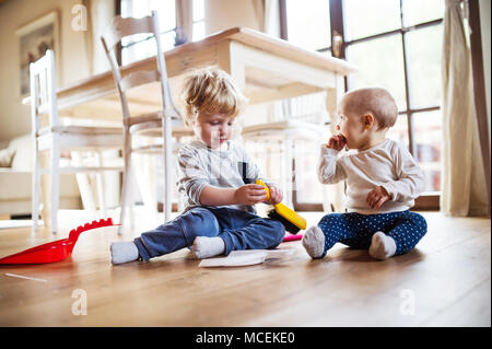 Zwei Kleinkinder mit Besen und Kehrblech zu Hause. Stockfoto