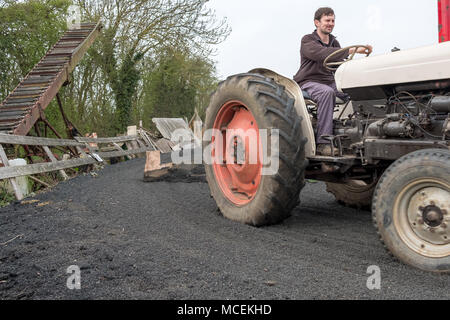 Vintage John Deere Traktor in restauriert werden von einem jungen Landwirt in einem livery Yard, die zerkleinerte Reifen wie ein Pferd Hof verwendet zu pflügen. Stockfoto