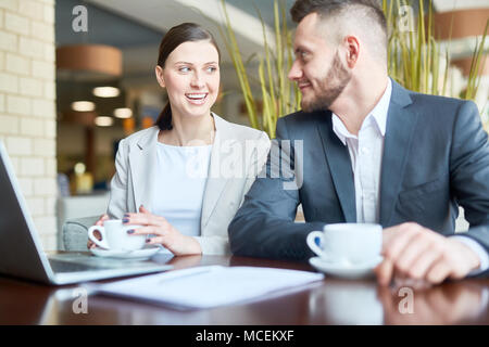 Junge kaukasier männlichen und weiblichen Büroangestellten plaudern und lächelnd, während im Cafe sitzen und warten auf das Mittagessen Stockfoto