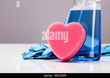 Blau transparent Reinigung Lösung In einem Kunststoffbehälter mit Herz Form Schwamm und Gummihandschuhe. Stockfoto