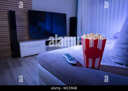 In der Nähe von Popcorn und Fernbedienung auf der Couch im Wohnzimmer bei Nacht Stockfoto