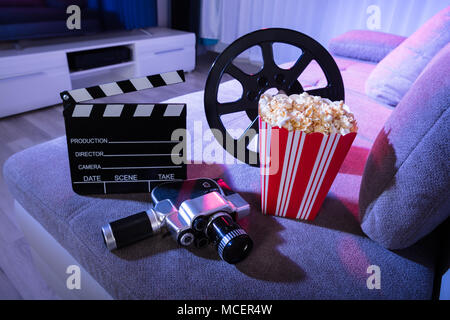 Close-up Film Kamera mit Klappe und Popcorn auf der Couch in der Nacht Stockfoto