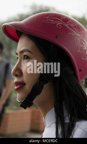 Eine elegante junge Frau trägt ein rot Designer Motorradhelm in Hanoi, Vietnam, Südostasien Stockfoto