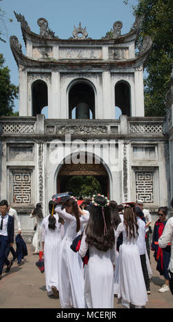 Mädchen in traditionellen Ao Dai Kleid zu ihrem Abschluss cermony durch die Van Mieu Tor am Eingang zum Tempel der Literatur in Hanoi, Vi Stockfoto