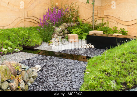 Stahl Wassertröge, Steinmauer, ply Zaun, bunte Blumen und Kies - 'Clear Waters Rising' Garten - RHS Flower Show, Tatton Park, England, Großbritannien Stockfoto