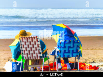 Cannon Beach, Oregon, USA - 28. September 2010: Zwei ältere Frauen bewaffnet mit Schirme, Hüte und Mäntel in Rasen sitzen ein Picknick auf t zu haben Stockfoto