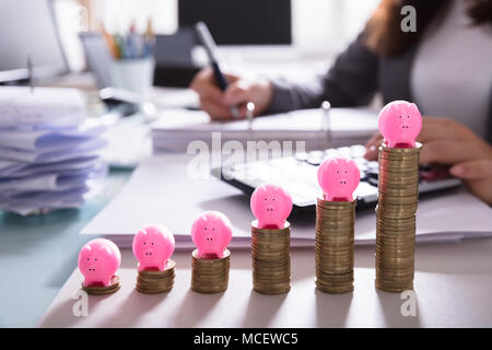 Rosa Sparschwein über Gestapelte Münzen Vor Geschäftsfrau Berechnung Rechnung Stockfoto