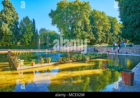 MAHAN, IRAN - Oktober 16, 2017: Die klare, frische Teich mit Triumphbögen, die von leuchtenden Blumen in Töpfe umgeben, Shazdeh Garten, am 16. Oktober in Mahan. Stockfoto