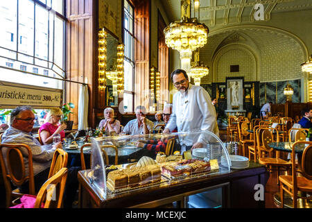 Prager Café im Inneren. Der Kellner serviert Kuchen für die Leute, Innenraum des Jugendstilcafes, Gemeindehaus Innenraum Tschechische Republik Prag Cafés Stockfoto