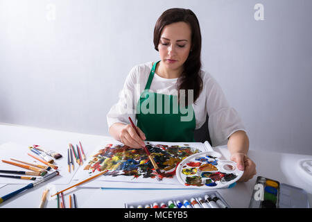 Nahaufnahme eines weiblichen Künstler Hand Farbpalette beim Malen auf Leinwand Papier Stockfoto