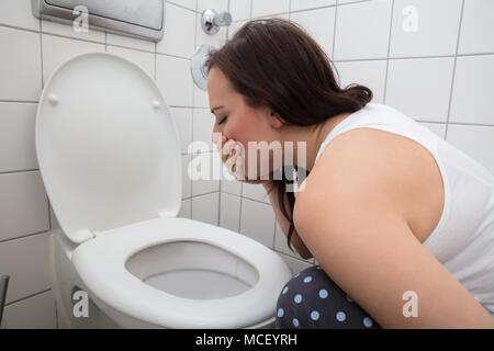 Nahaufnahme einer jungen Frau Erbrechen In der WC-Schüssel Stockfoto