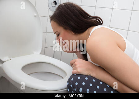 Nahaufnahme einer jungen Frau Erbrechen In der WC-Schüssel Stockfoto