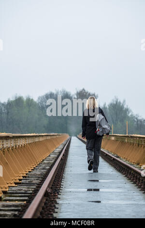 Frau mit Rucksack wandern einsam auf einer verlassenen lange Eisenbahnbrücke aus Stahl Stockfoto