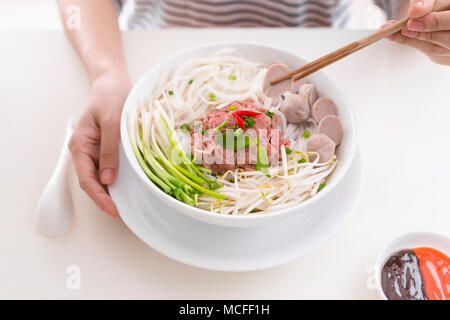 Frau essen traditionellen vietnamesischen Pho Nudeln mit Stäbchen. Stockfoto