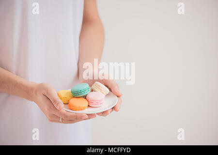 Hände, die farbenfrohen Pastelltönen Kuchen macarons oder Makronen Stockfoto