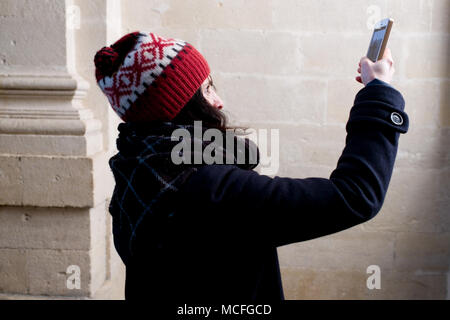 Attraktive französische Frau mittleren Alters mit Bommel hat nimmt ein Foto mit Ihrem Smartphone in der alten Kirche Stockfoto