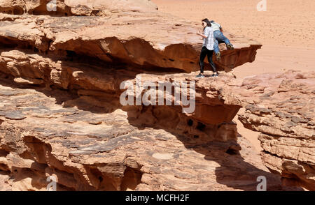 Wadi Rum, Jordanien, 8. März 2018: Chinesische Touristen klettern über die natürliche Brücke aus Stein in der Wüste Naturschutzgebiet Stockfoto