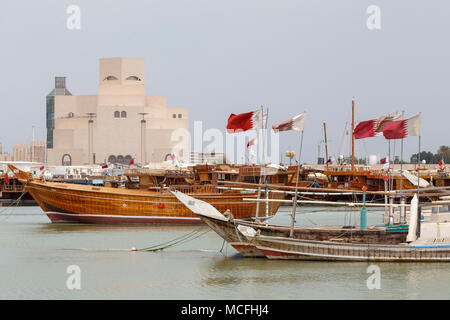 DOHA, Katar - 16. April 2018: Verschiedene traditionelle Holzboote fliegen die Katarische Fahne vor der Sehenswürdigkeit Museum für Islamische Kunst Stockfoto